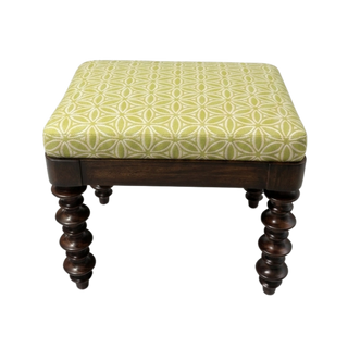 Wooden stool with a patterned green cushion on a white background