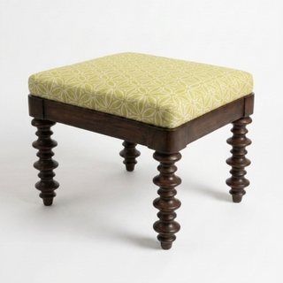 Wooden stool with a yellow patterned cushion on a white background