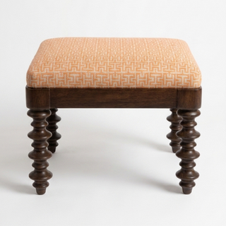 Stool with patterned orange cushion and wooden legs on a white background