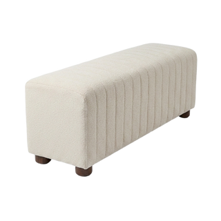 A rectangular upholstered bench with vertical channel tufting on the seat, upholstered in a textured cream fabric, supported by four dark brown wooden legs, shown on a plain white background.