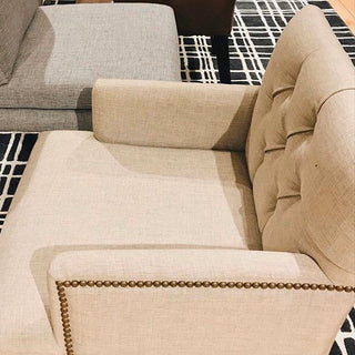 Beige upholstered chair with decorative nailhead trim